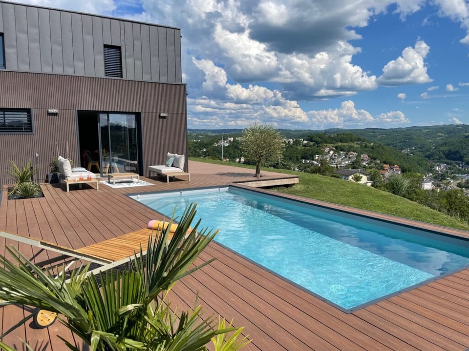 terrasse composite ultraprotect teinte ipé avec piscine contours cornières alu et vue sur les montagnes 