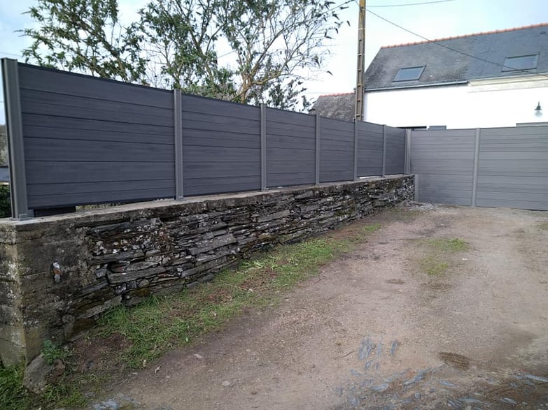 clôture en bois composite ultraprotect teinte anthra sur mur de clôture en pierre