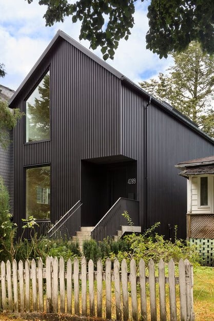 Maison entièrement recouverte d'un revêtement en faux claire voie noir